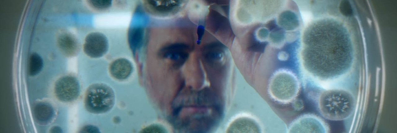 Hombre mirando por encima de una placa de Petri con bacterias